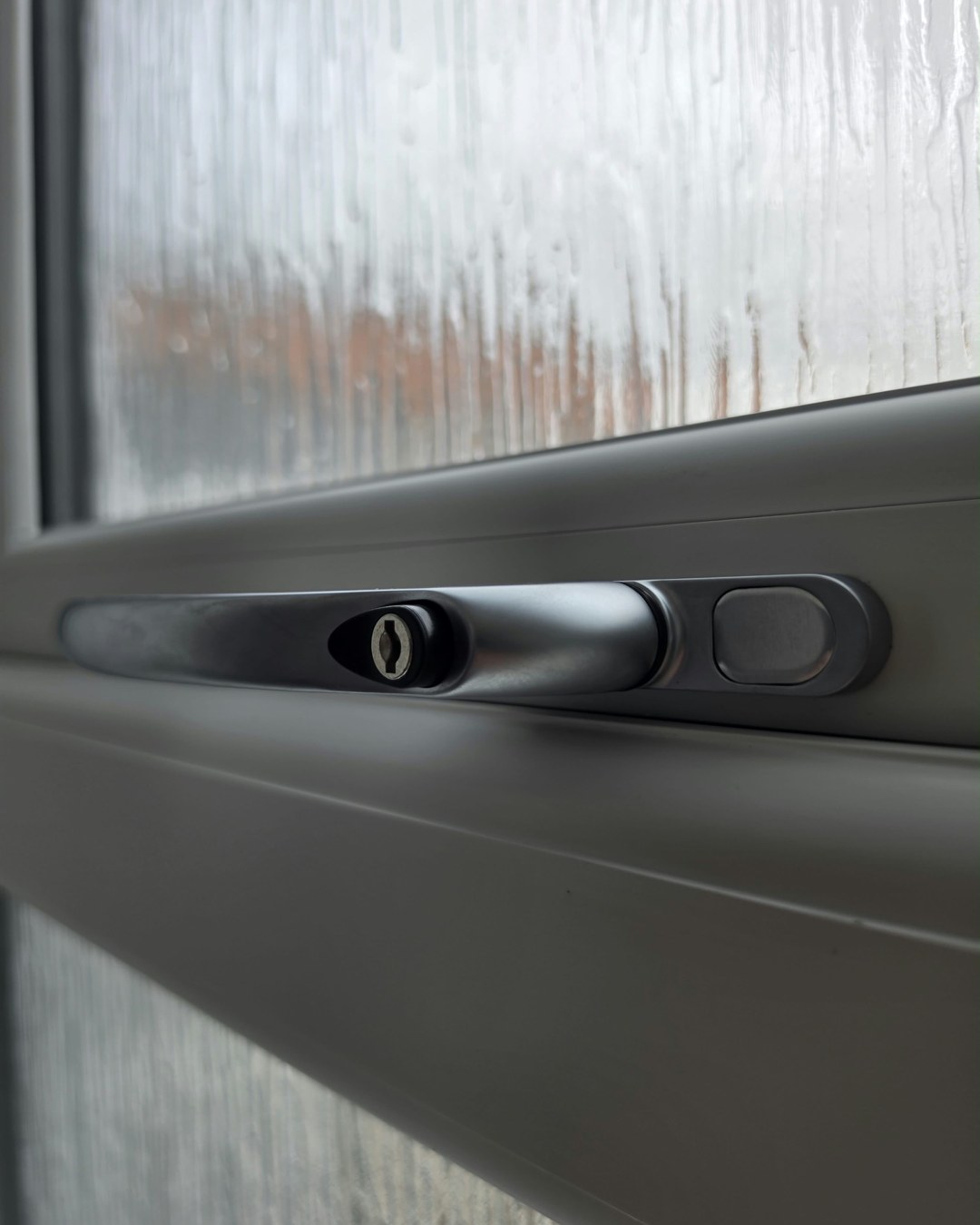 Close-up of a new lockable window handle on a white window with obscure glass at Logan Primary School