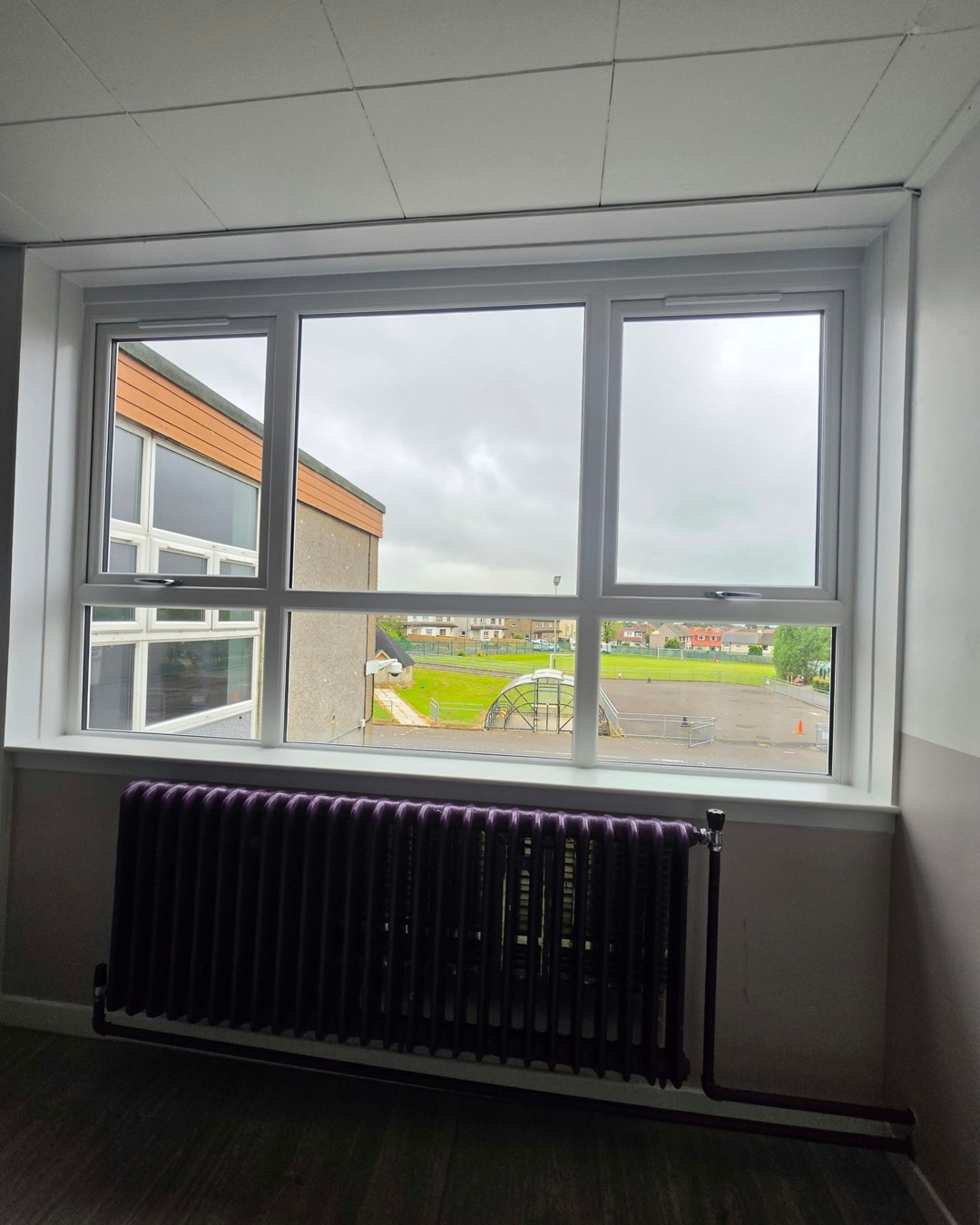 Inside a classroom at Logan Primary School, looking out through a new white window towards the playing fields
